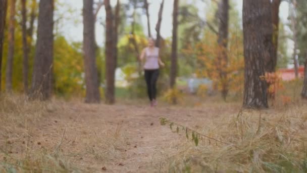 Улыбающаяся женщина сняла видео с палкой для селфи, как она бежит в лесу — стоковое видео