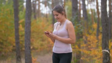 Güzel ve genç birbayan ormanı koşu önce smartphone cep telefonu ile müzik parçasını seçme