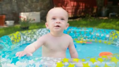 Şirin neşeli bebek çocuk annesi şişme havuzda süre ile oynarken