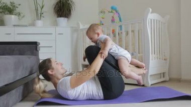 Genç anne ile onun bebek çocuk fitness mat oturma odasında egzersiz