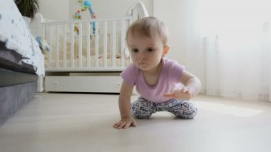 Kameraya doğru yerde sürünerek sevimli gülümseyen yürümeye başlayan çocuk