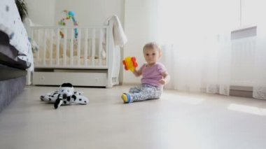 Dolly atış yatak odası ve oyuncaklar ile oynama katta oturan sevimli yürümeye başlayan çocuk