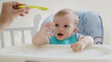 Eğleniyor ve sandalyesi püresi yerken oynayan neşeli bebek çocuk