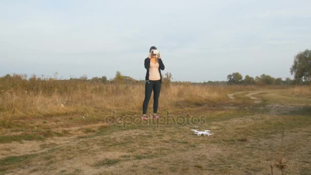 Молодая женщина в FPV гарнитуре и управляющий полет квадрокоптера — стоковое видео