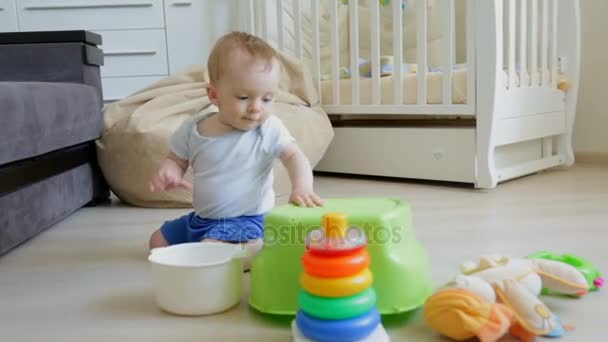 Симпатичный мальчик сидит на полу в гостиной и играет с игрушками — стоковое видео