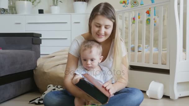 Gelukkig jonge moeder kijken naar foto's in de familie-album met haar zoontje — Stockvideo