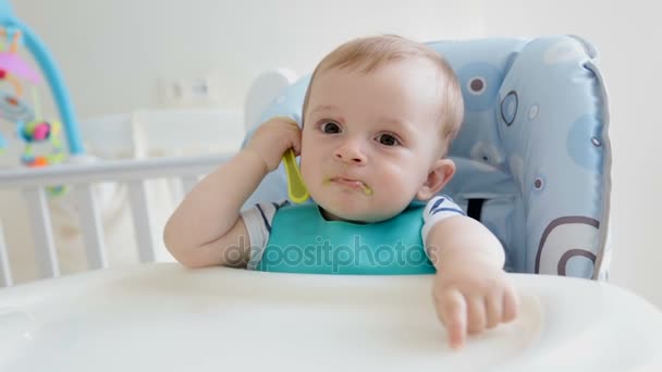 Cute baby boy playing with spoon while eating porridge — Stock Video