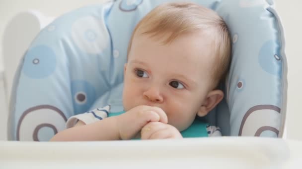 Schattige babyjongen eten van soep met een lepel door hemzelf en krijgen rommelig — Stockvideo