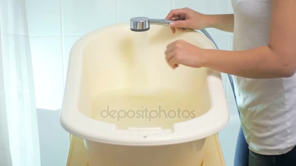 Imágenes de primer plano 4K de la madre joven comprobando la temperatura del agua en el baño del bebé — Vídeos de Stock