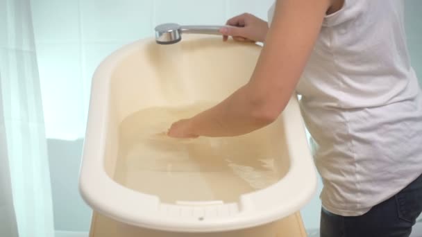 Slow motion footage of young caring mother checking temperature at baby's bath — Stock Video