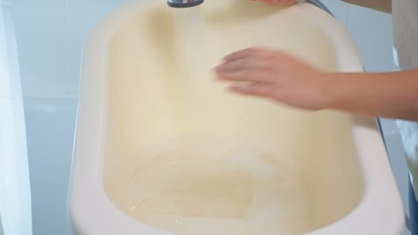 4K відео матері, що наповнює дитячу ванну водою та піною — стокове відео