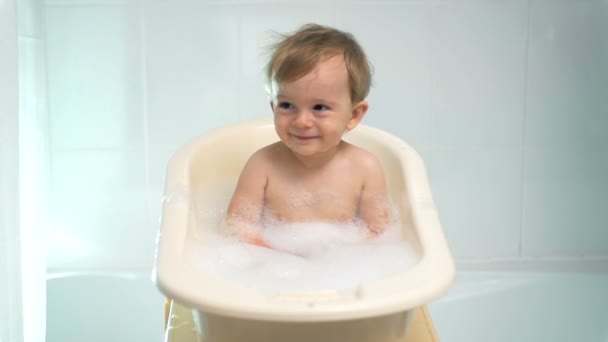 Banyoda oturan sevimli gülen erkek bebek yavaş çekim görüntüleri — Stok video