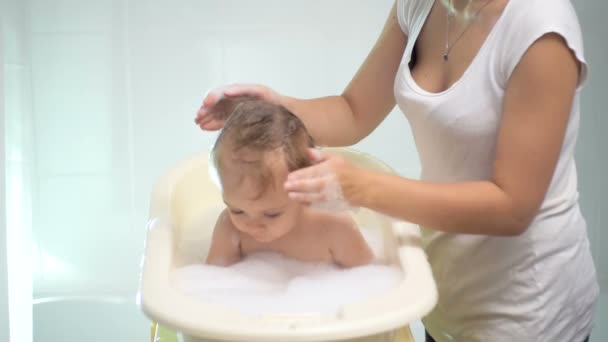 Mouvement lent de la mère laver la tête du bébé avec un shampooing — Video