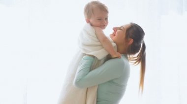 Mutlu genç anne bebek oğlu büyük pencerede sarılma ağır çekim görüntüleri