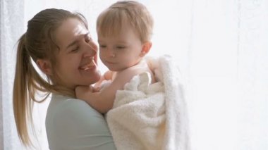 Ağır çekim portre görüntüleri mutlu gülümseyen anne bebek oğlu yatak odası penceresinde, sarılma