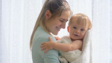 Ağır çekim görüntüleri bir havlu büyük pencerede sarılma içinde şirin bebek ile anne