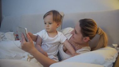 yatakta yatan ve dijital tablet kullanma bebek evlat annenle 4 k video
