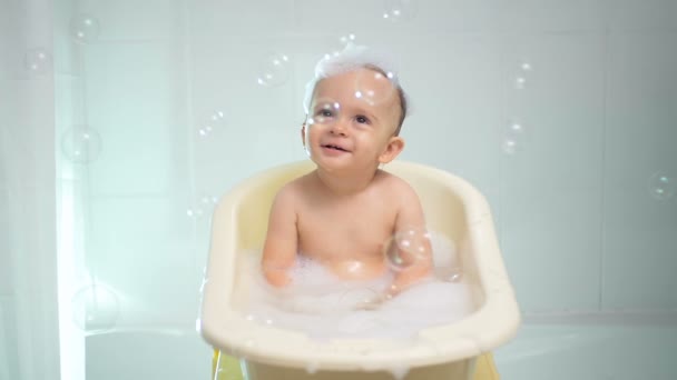 Zeitlupenaufnahmen eines fröhlichen Jungen, der in der Badewanne spielt — Stockvideo