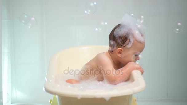 비누 거품과 거품 목욕을 즐기는 귀여운 아기의 슬로우 모션 비디오 — 비디오