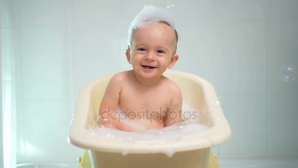 Slow motion séquences de joyeux rire bébé garçon profiter de bain avec des bulles de savon — Video
