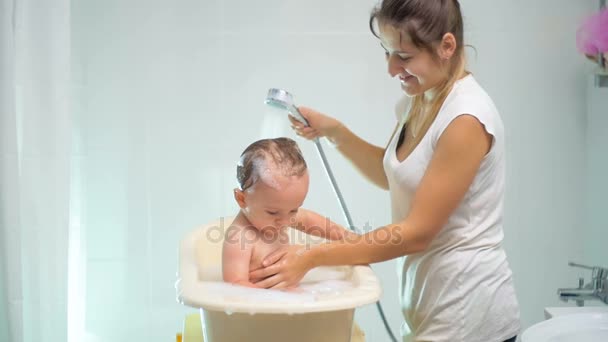 Zeitlupenaufnahmen von junger Mutter, die ihren kleinen Sohn in der Badewanne wäscht — Stockvideo