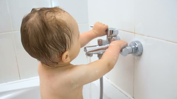 Closeup 4k beelden van schattige peuter jongen opent water kraan in de badkamer — Stockvideo