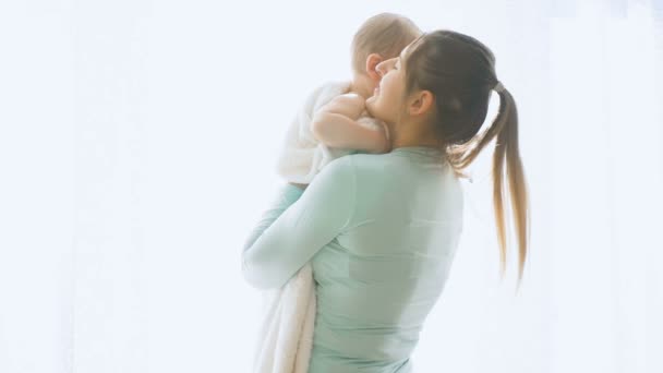Zeitlupenaufnahmen von Mutter, die ihr Baby am großen Fenster hält und kuschelt — Stockvideo