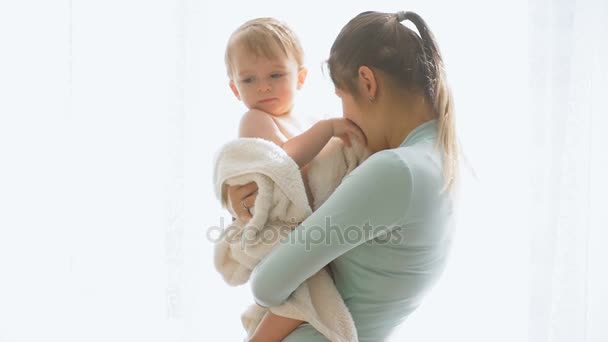 Filmagem em câmera lenta de bebê bonito menino abraçando a mãe na grande janela — Vídeo de Stock
