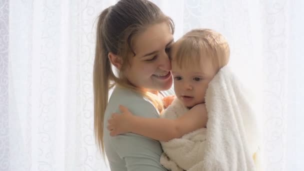 Красива дбайлива мати обіймає свого сина, вкритого ковдрою — стокове відео