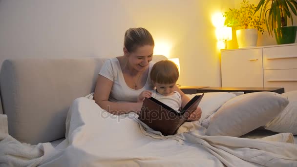 4k video de madre joven leyendo libro a su hijo pequeño en la cama — Vídeos de Stock