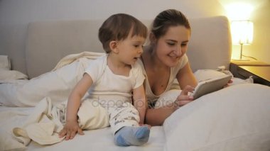 Mutlu gülümseyen bebek çocuk annesi yatak ile dijital tablet kullanma