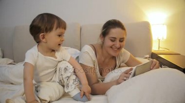 genç anne bebek evlat dijital tablet vasıl yatak üzerinde oyun ile 4 k görüntüleri