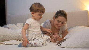 Uykusuz bebek ile annesi izlerken çizgi film tablet, yatak odası