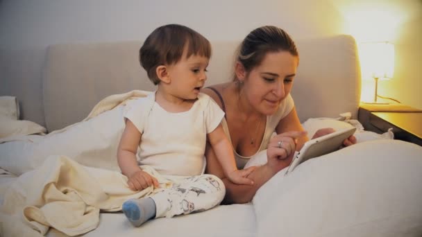 Matka z dzieckiem za pomocą tabletu przed pójściem spać — Wideo stockowe