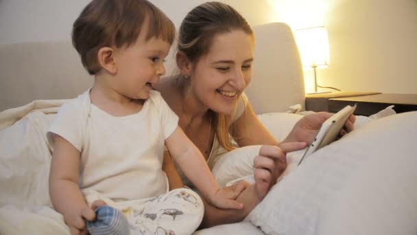 Closeup 4k imagens de mãe feliz com o bebê filho brincando no tablet digital à noite — Vídeo de Stock