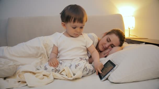 4k видео ребенка отказывается спать и смотреть мультфильмы на цифровом планшете — стоковое видео