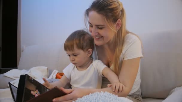 4k imagens de bela mãe com bebê menino assistindo fotografias na cama — Vídeo de Stock