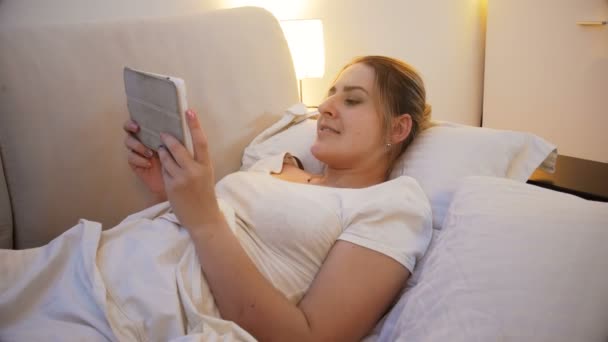 4k Nahaufnahme junge Frau liest Buch auf digitalem Tablet am Bett — Stockvideo