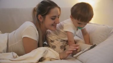 şirin bebek çocuk ile anne yatakta yatan ve tablet video izlerken 4 k closeup çekim