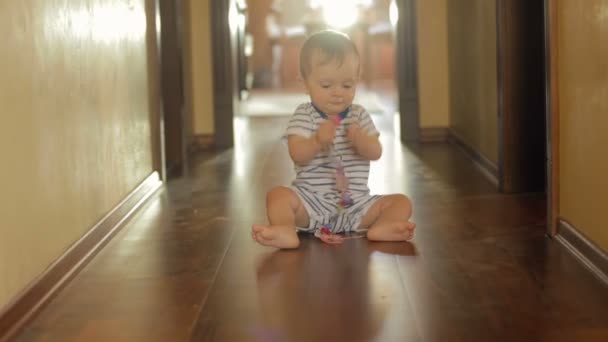 Bonito menino sorridente sentado no chão e deitado com brinquedos — Vídeo de Stock