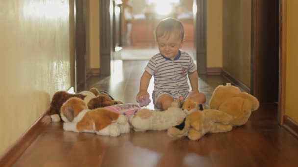 Lindo niño sonriente jugando en el suelo con juguetes de peluche — Vídeo de stock