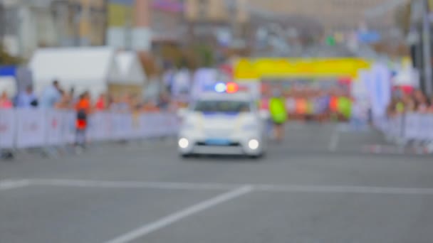Samochód policyjny z syreny i światła włączone czeka na początku city marathon — Wideo stockowe