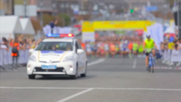 Carro de polícia levando corredores da linha de partida no dia da maratona da cidade — Vídeo de Stock