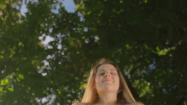 Aşağı bükme ve kamera bahçede bakarak mutlu gülümseyen genç kadın portresi