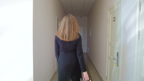 Steadicam slow motion shot of elegant businesswoman pulling suitcase at hotel hall — Stock Video