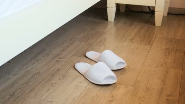 Closeup shot of young woman waking up and wearing white slippers at hotel — Stock Video