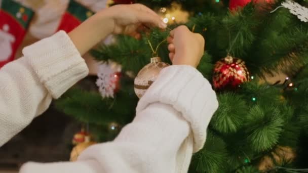 特写镜头的女孩装饰圣诞树。镜头拉近从手到摆设 — 图库视频影像