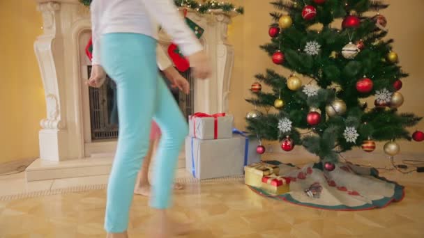 Två glada tjejer i pyjamas med julklappar och öppna dem. — Stockvideo