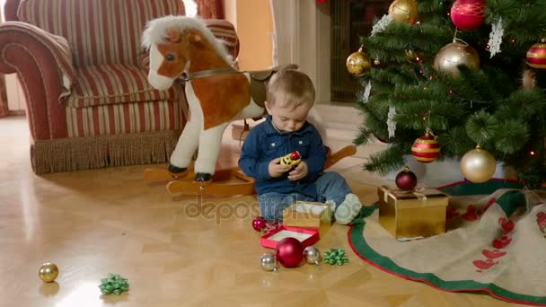 Adorável menino de 1 ano de idade jogando sob a árvore de Natal na sala de estar — Vídeo de Stock