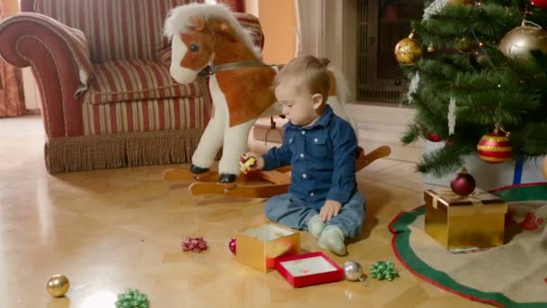 Bonito menino brincando com brinquedos no chão sob a árvore de Natal — Vídeo de Stock